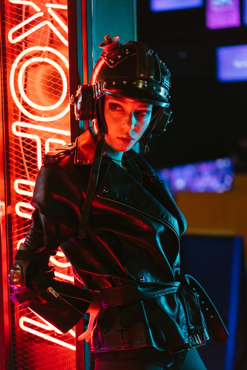 Striking cyberpunk fashion portrait featuring a woman in futuristic attire beside neon lights.
