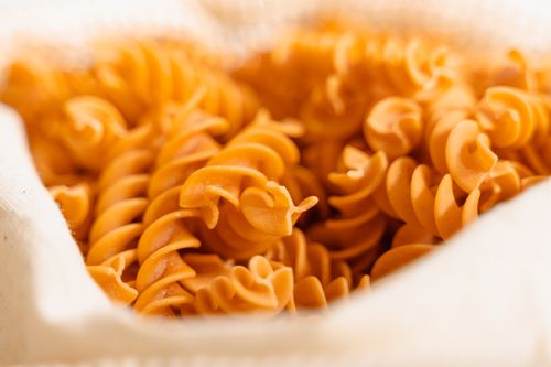 Free A detailed close-up of uncooked fusilli pasta spirals in a burlap sack, highlighting texture and color. Stock Photo