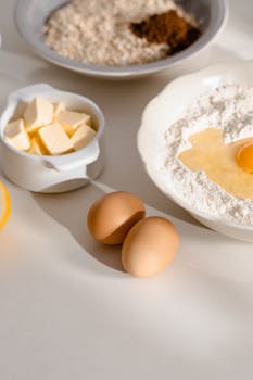 Flour, eggs, and butter ready for a homemade baking recipe, creating a rustic kitchen vibe.