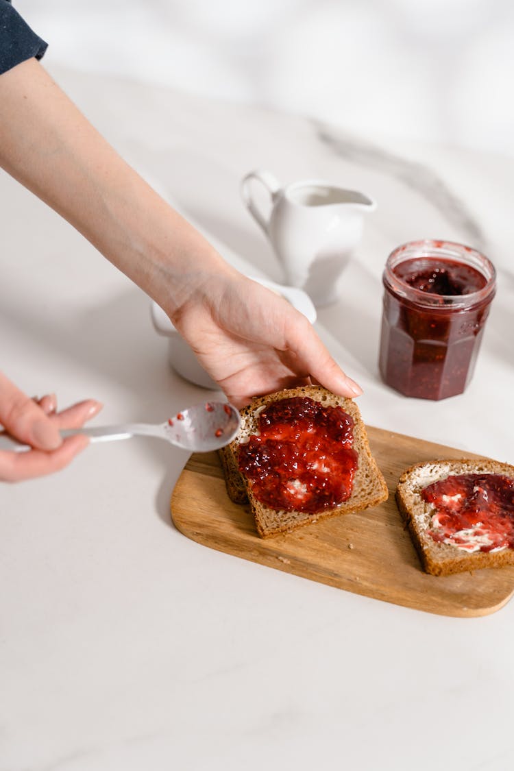 Person Spreading Jam On Toast 