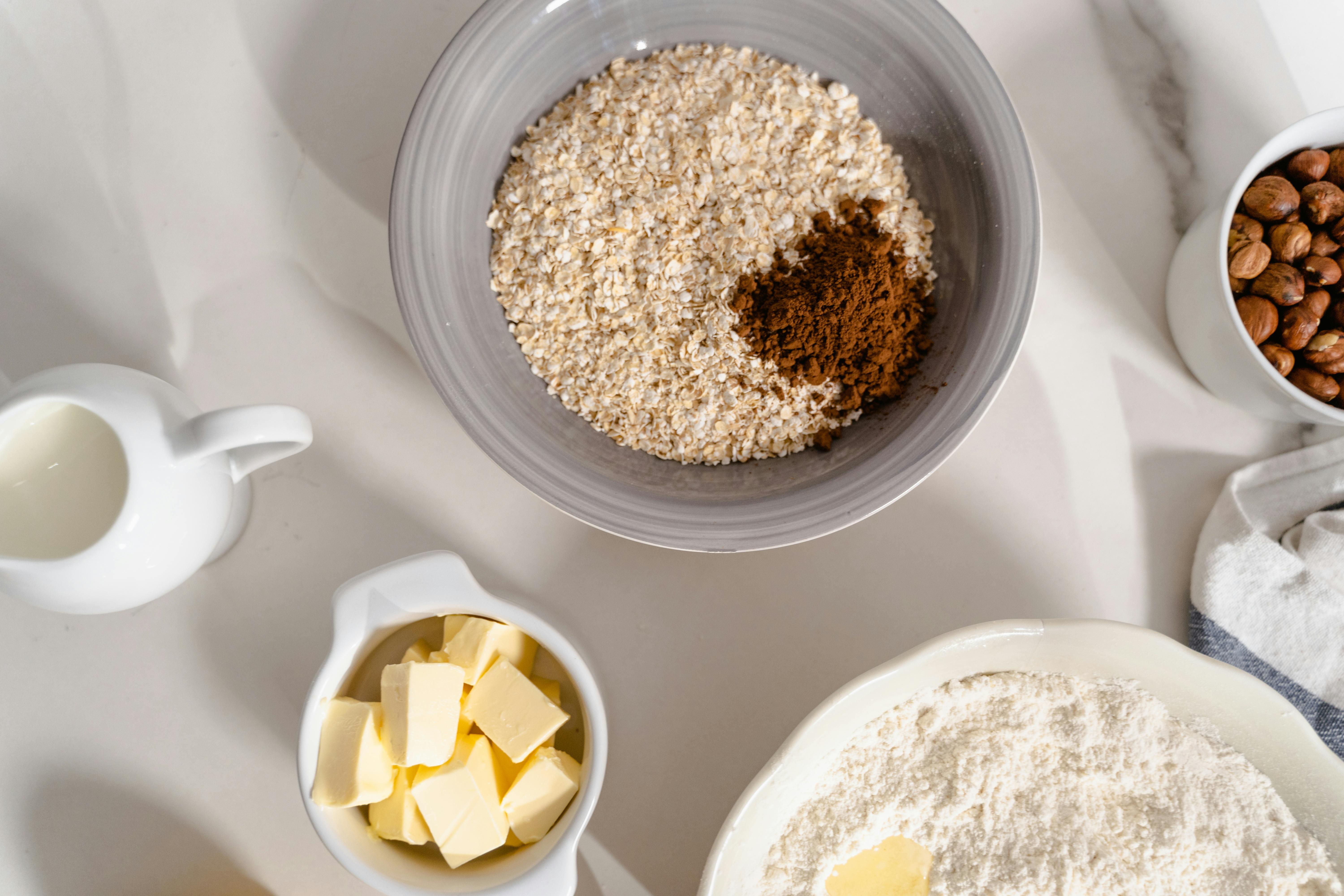 oatmeal and brown powder in a ceramic bowl on a white surface