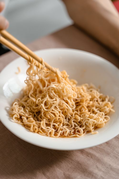 Free Close-up of savory noodles in a ceramic bowl with chopsticks, highlighting Asian cuisine. Stock Photo