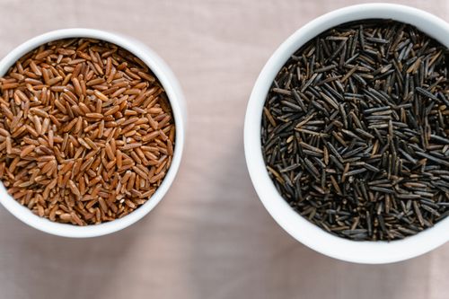 Free High-angle view of brown and black rice in ceramic bowls on a white surface. Stock Photo