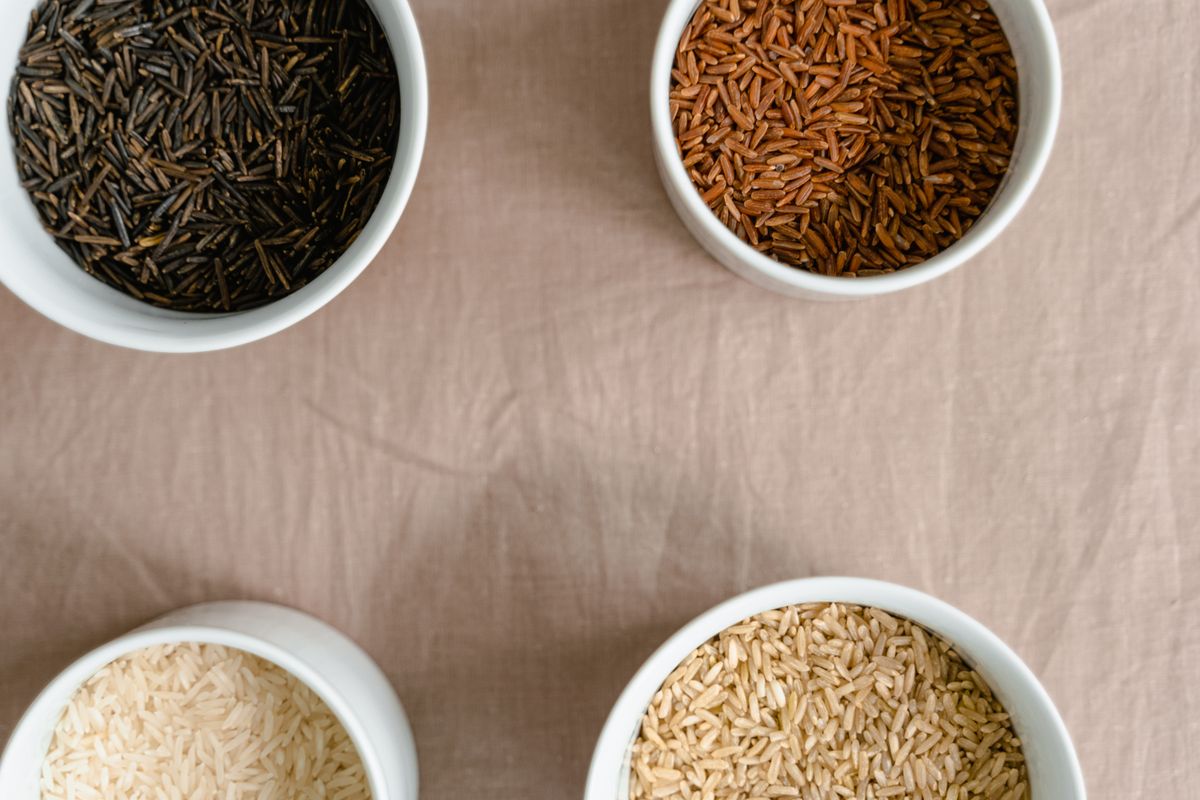 Overhead view of four ceramic bowls holding different varieties of rice. Photo by MART PRODUCTION on Pexels