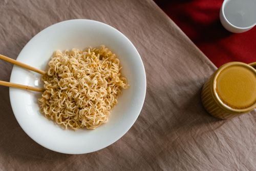 Free A delicious serving of instant noodles in a white bowl with chopsticks on a textured table. Stock Photo