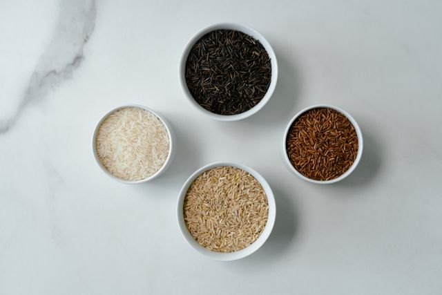 Four white bowls holding wild rice, red rice, brown rice and white basmati
