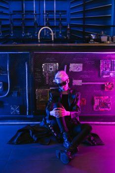 A stylish woman in cyberpunk attire sits under vibrant neon lights, exuding futuristic vibes.