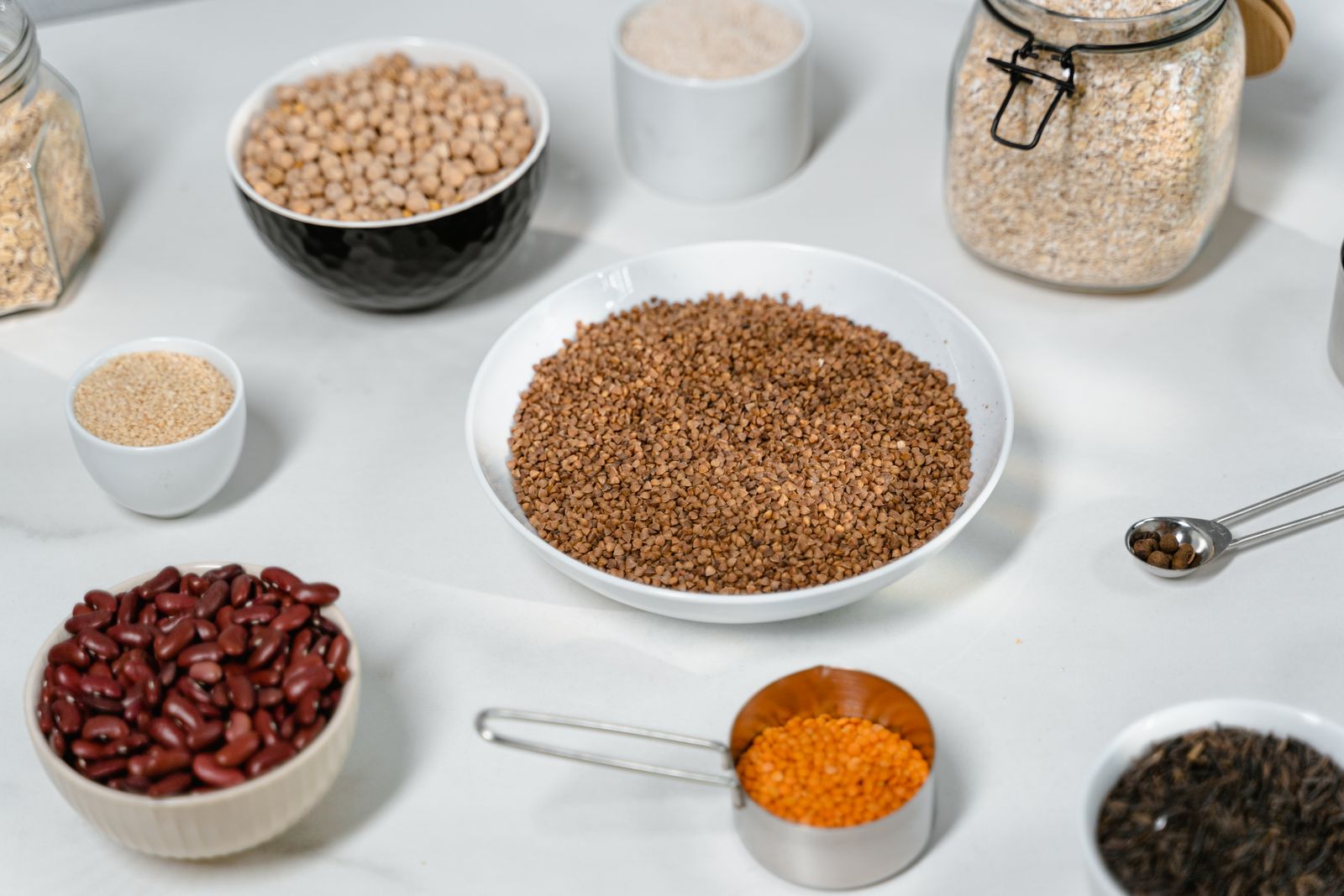 Bowls of oats, beans, lentils, and grains on a plain surface, showing a mix of soluble and insoluble fiber foods