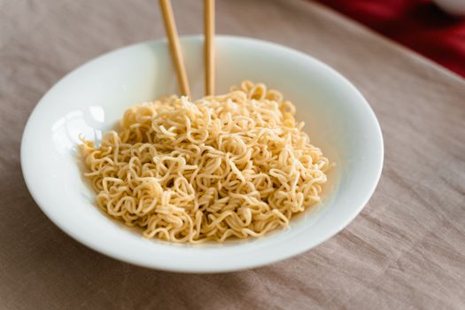 A close-up shot of plain noodles in a white bowl with chopsticks, perfect for Asian cuisine themes.