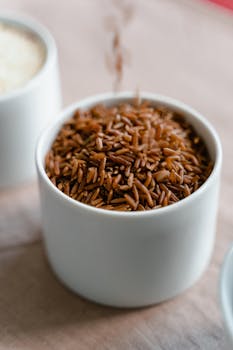 A detailed close-up shot of brown rice in a white ceramic cup, showcasing texture.