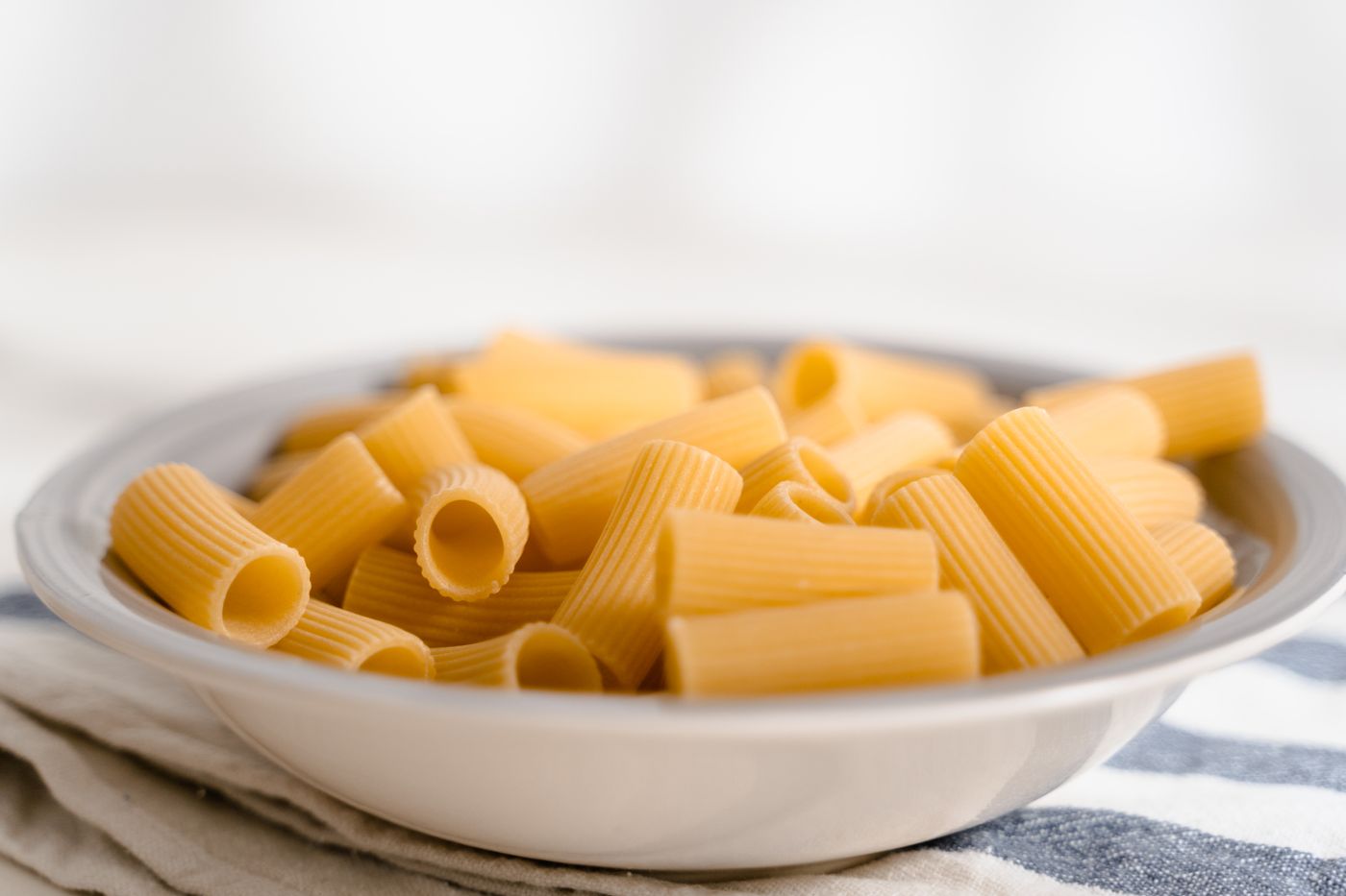 High-quality close-up of a bowl of raw rigatoni pasta, perfect for Italian cuisine themes.