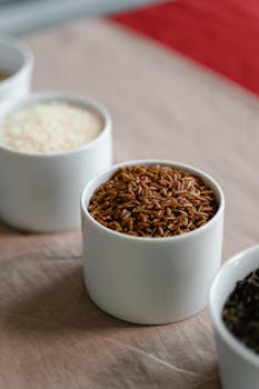 Close-up of a variety of grains in white cups, showcasing textures and colors.