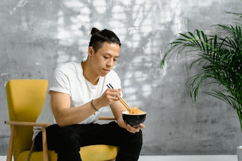 Free Man Sitting on Chair Eating with Noodles Stock Photo