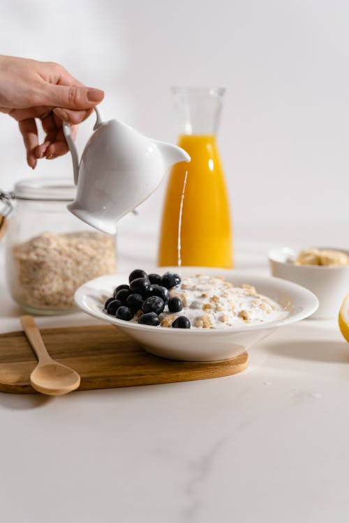 Free A Person Pouring Milk on an Oatmeal Stock Photo