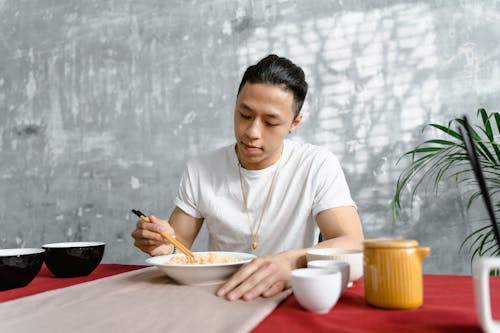 Man in White Short Eating with Chopsticks