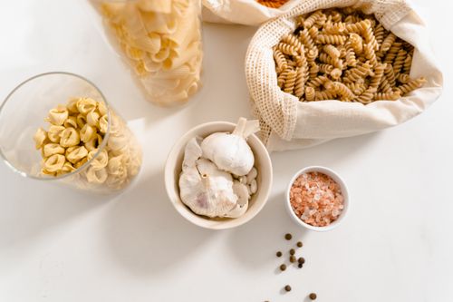 Free A top view of organic pasta ingredients and seasonings, featuring garlic, pink salt, and reusable bags. Stock Photo