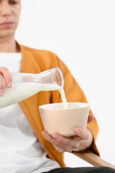 Close-up of a person pouring milk from a bottle into a textured bowl.