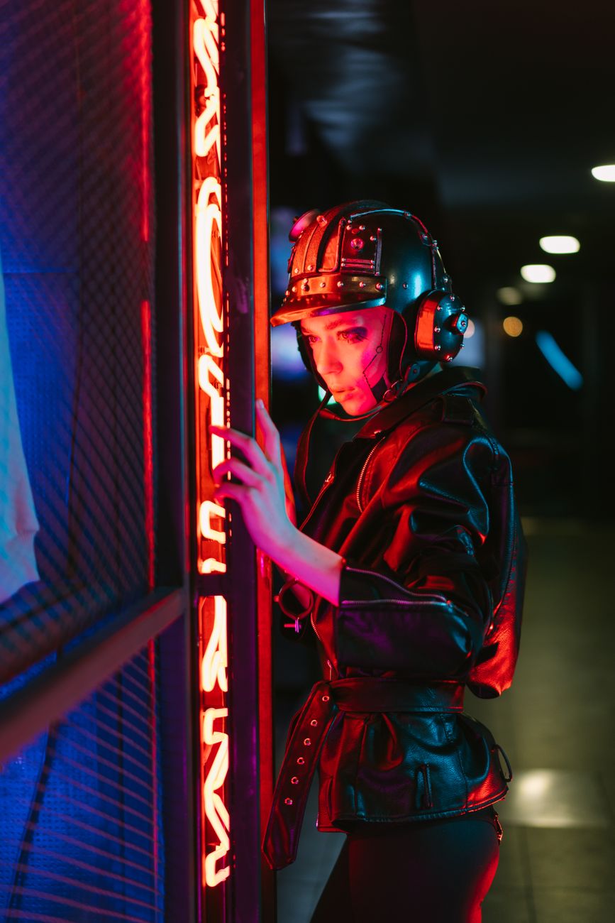 Woman in a cyberpunk helmet and jacket with vibrant neon lighting.
