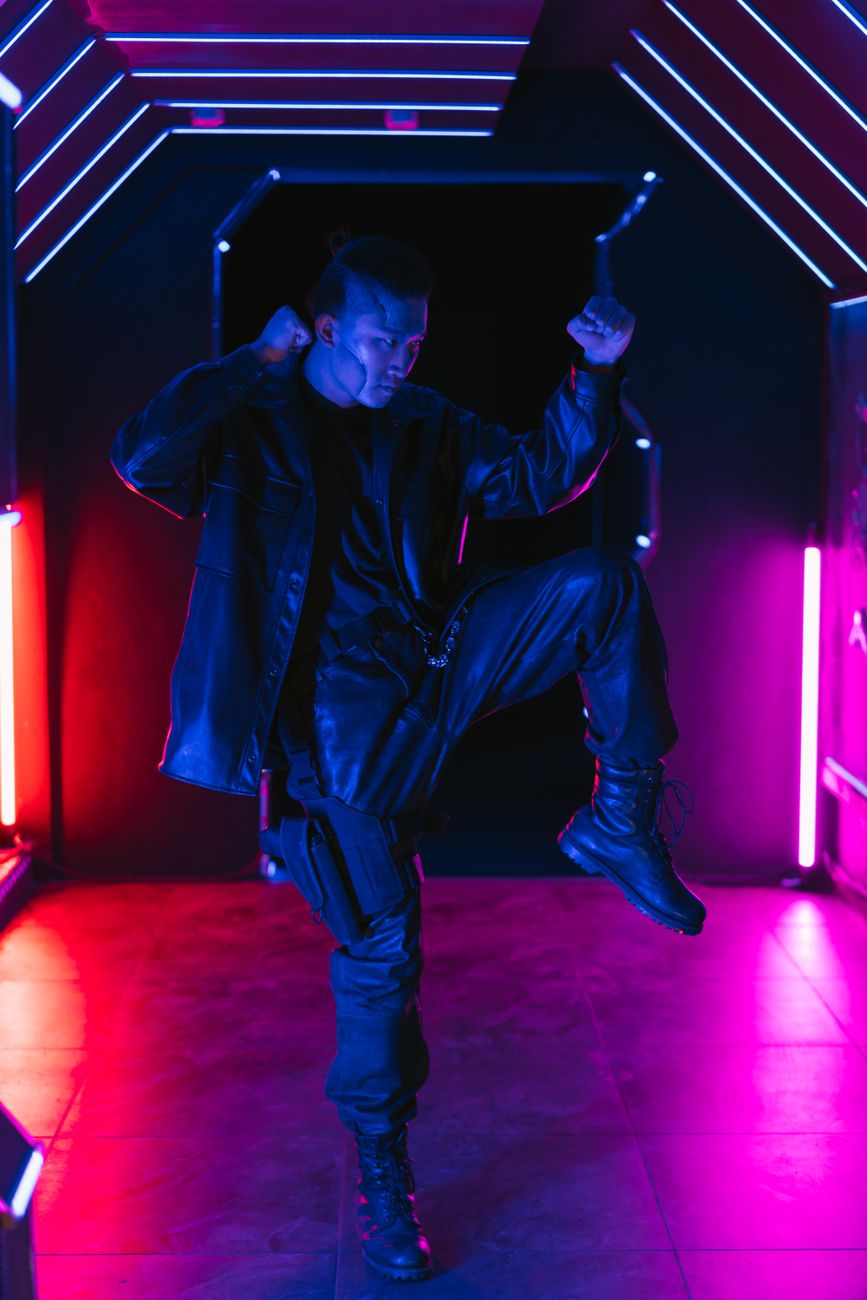 A person striking a bold pose in a neon-lit corridor, showcasing futuristic cyberpunk fashion style.. pexels, person, strikin