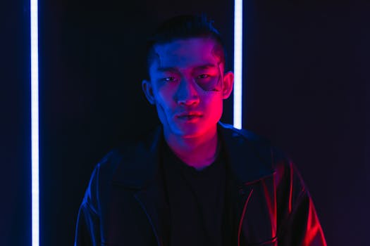 Asian man with futuristic makeup under neon lights in cyberpunk theme.