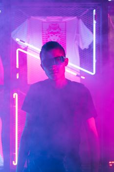 Futuristic portrait of a man wearing sunglasses in a neon-lit environment.