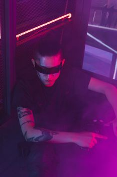 Stylish cyberpunk portrait of a man in neon lights wearing sunglasses.