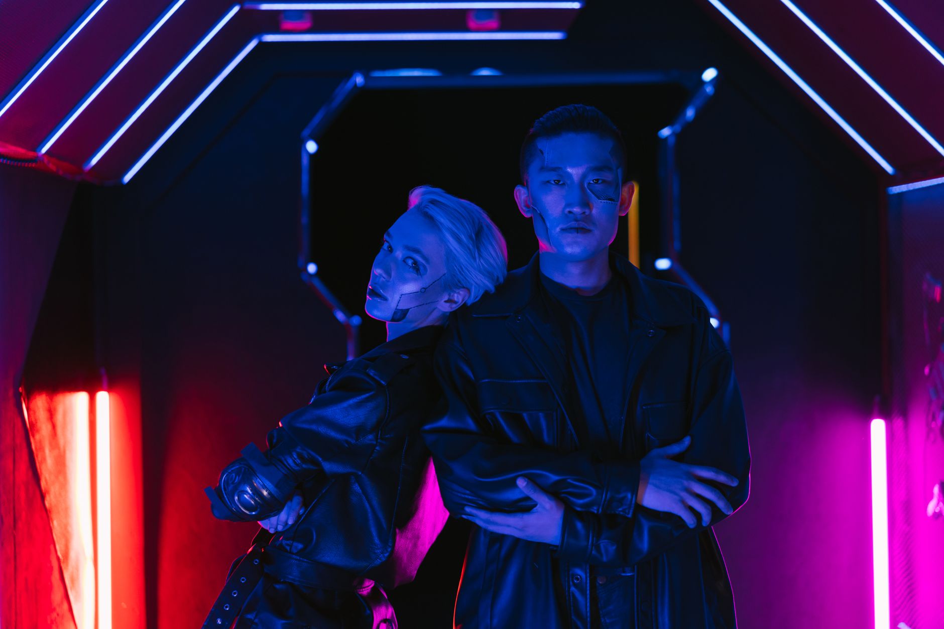 Two stylish individuals in a cyberpunk setting embracing futuristic fashion under neon lights.
