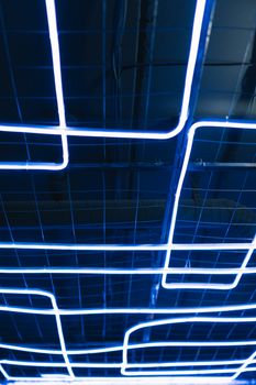 Abstract blue neon light art installation with geometric patterns on a grid.