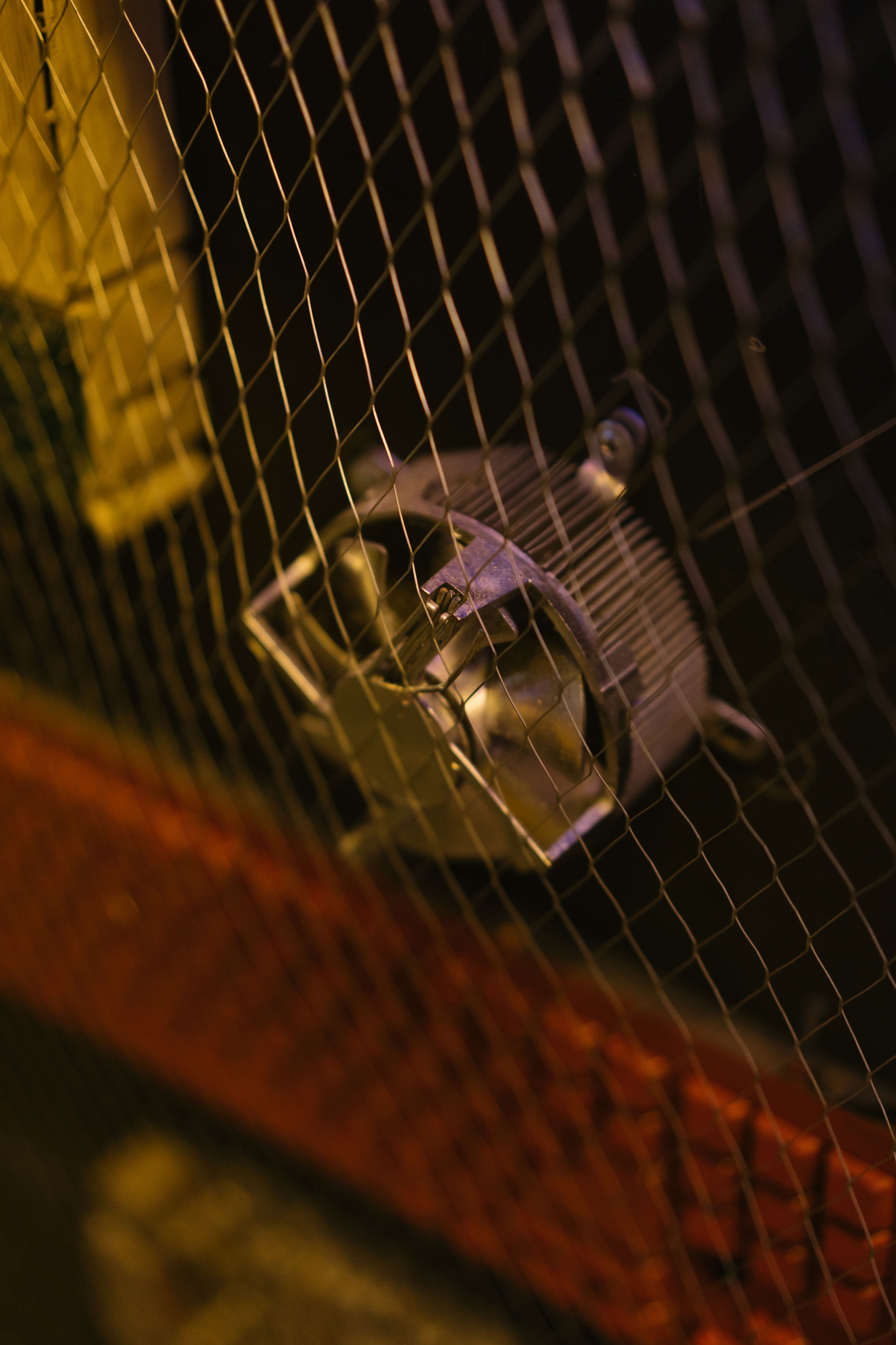 Ventilateur d'extraction protégé par une grille métallique dans un local peu éclairé