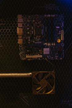 A detailed view of a motherboard and computer fan mounted on a mesh surface.
