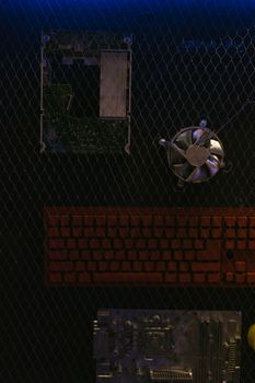 Overhead view of computer parts on a wire mesh with dramatic lighting.