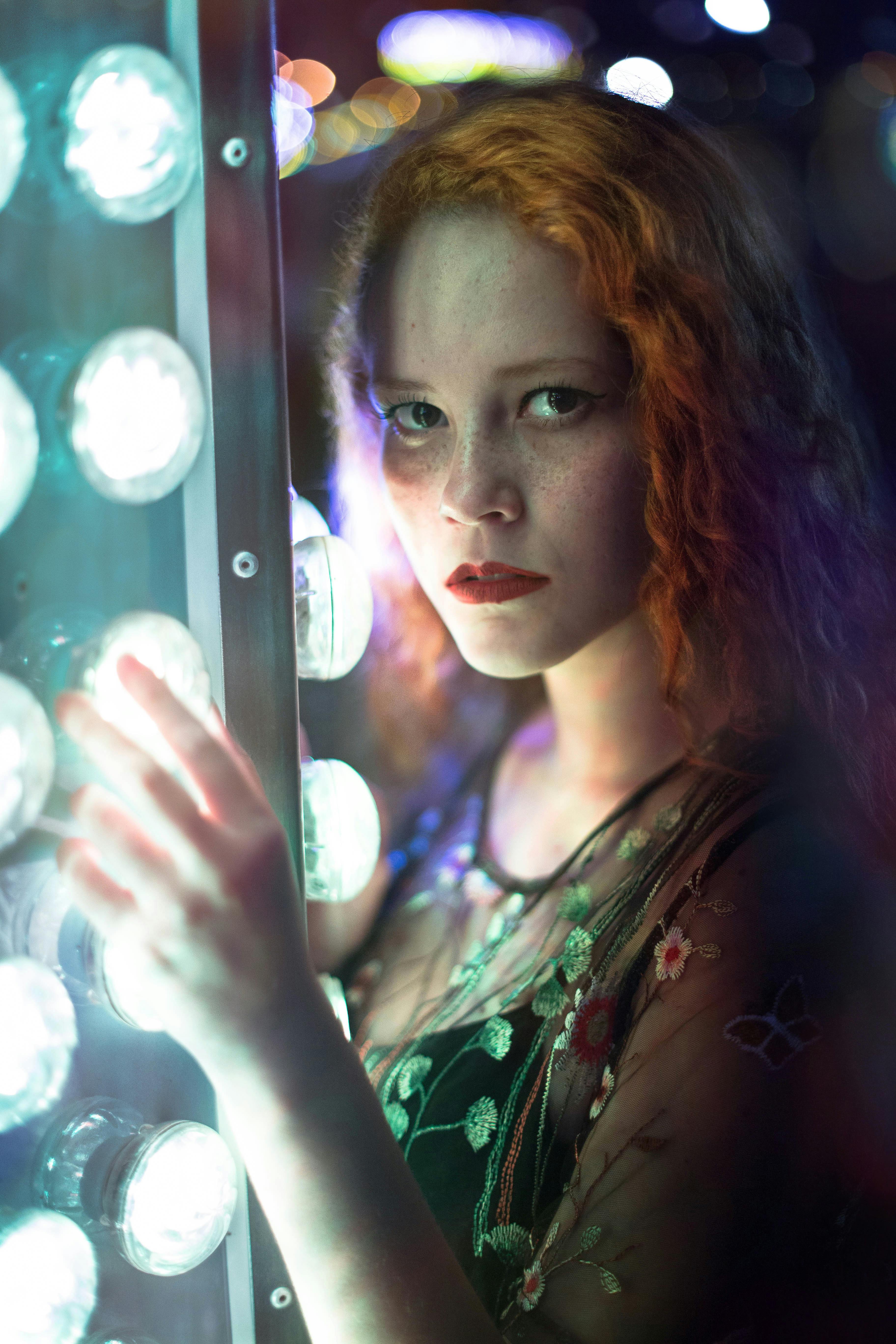 一幅以发光灯光为背景的红发女子肖像引人注目，展现了现代时尚与优雅