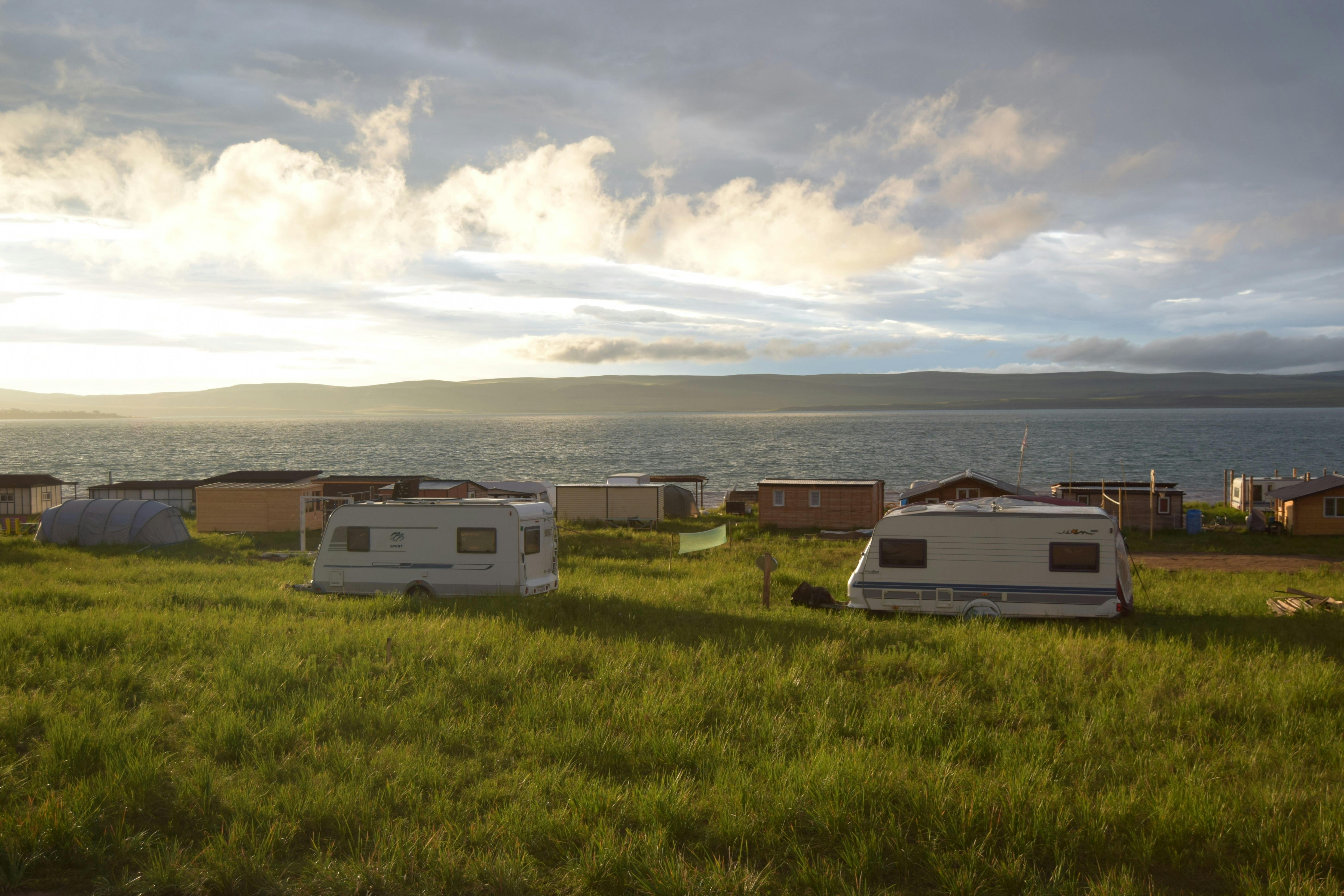 Tranquil coastal camping scene with parked camper vans by the ocean. Scenic and serene setting.