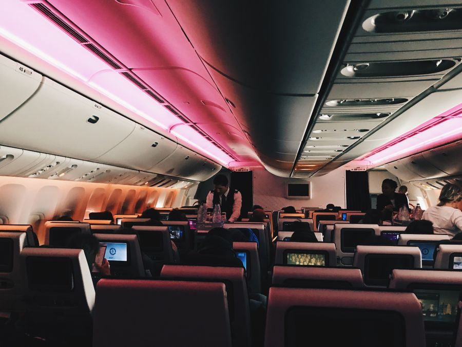 A dimly lit airplane cabin at night with passengers in their seats and seatback screens glowing