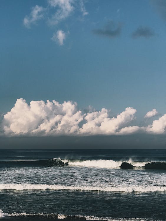 Waves Rushing to Shore under Blue Sky with White Clouds