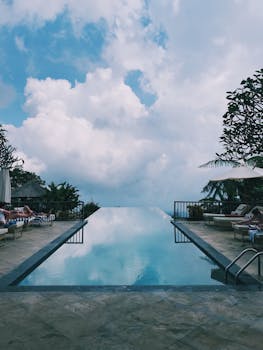 Infinity pool overlooking lush greenery under a bright blue sky, perfect for relaxation.