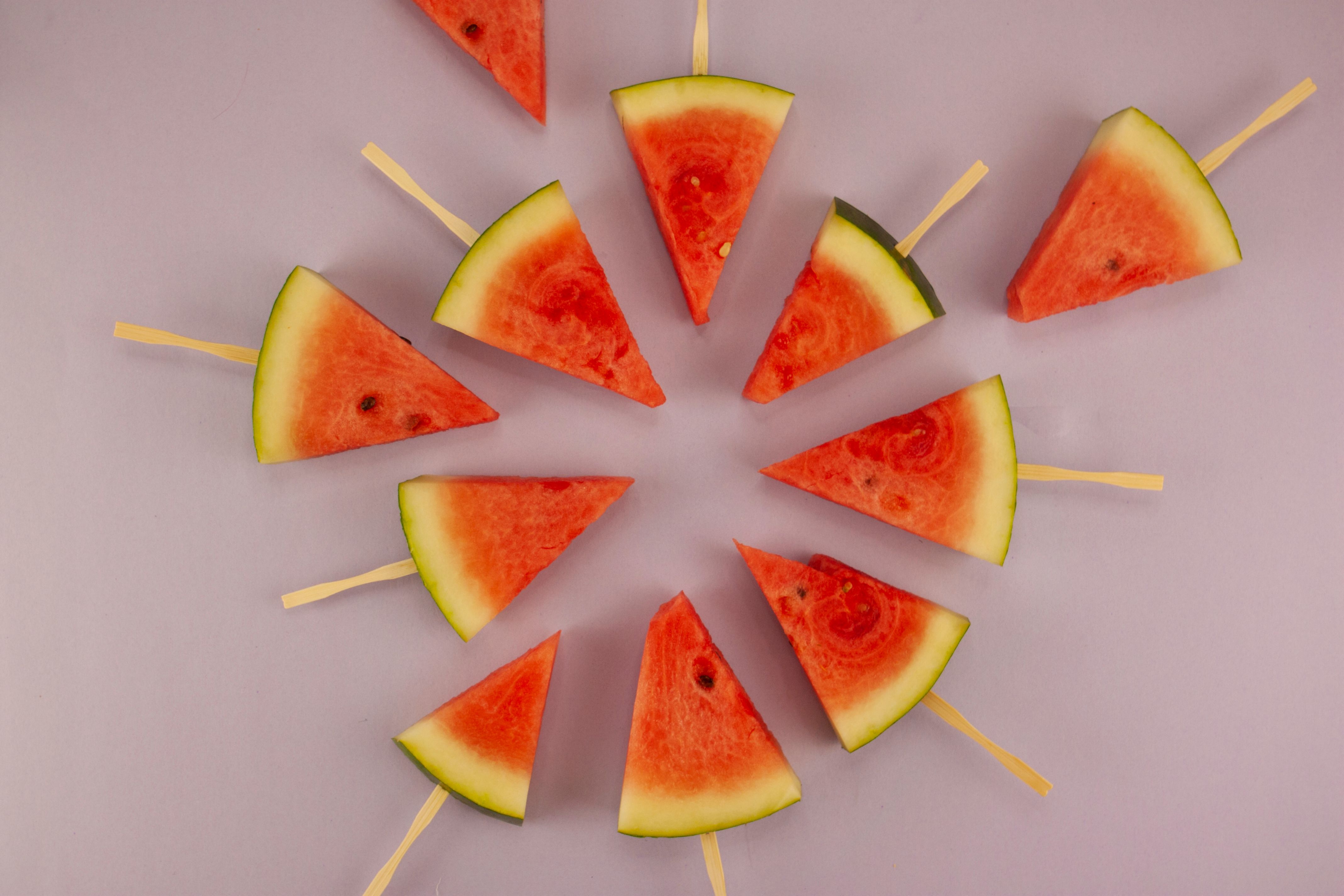 A vibrant array of watermelon popsicle slices arranged on a pink backdrop, showcasing summer freshness.