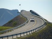 一辆汽车行驶在标志性的大西洋公路上，沿途可欣赏海岸景观和蜿蜒的建筑