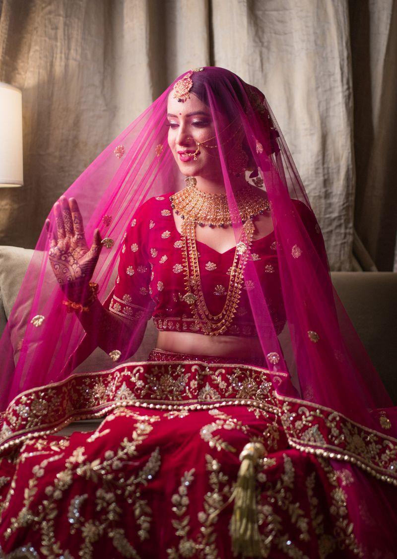 Elegant Indian bride in red traditional dress with intricate gold jewelry