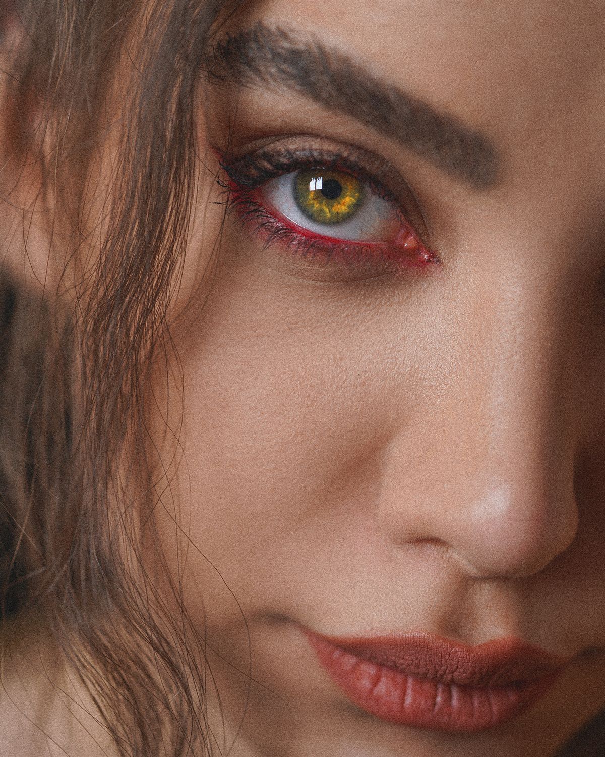 Warm hazel-green eye makeup close-up with red liner