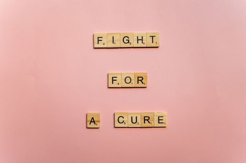 Free Wooden letter tiles on a pink background spell 'Fight for a Cure'. Motivational design. Stock Photo