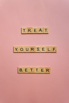 Scrabble tiles spelling 'Treat Yourself Better' on a pink background.