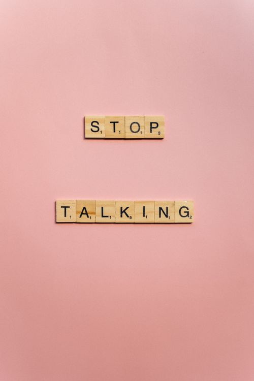 Free Wooden Scrabble tiles spelling 'STOP TALKING' on a pink background. Stock Photo