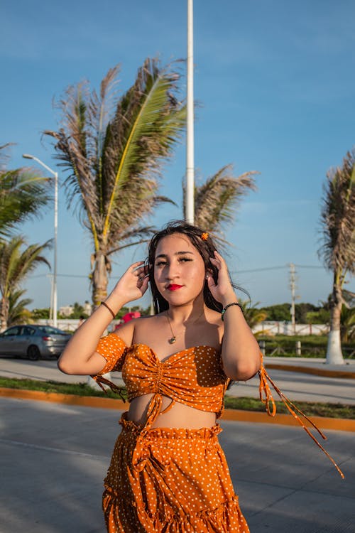 Young Woman in a Summer Outfit on the Background of Palm Trees