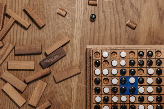 Flat lay of a strategy board game with wooden pieces and a game board on a wooden table.