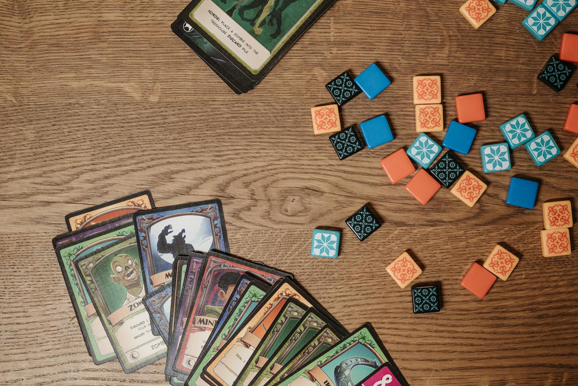 Top view of colorful board game cards and tokens on a wooden table, suggesting playful entertainment.