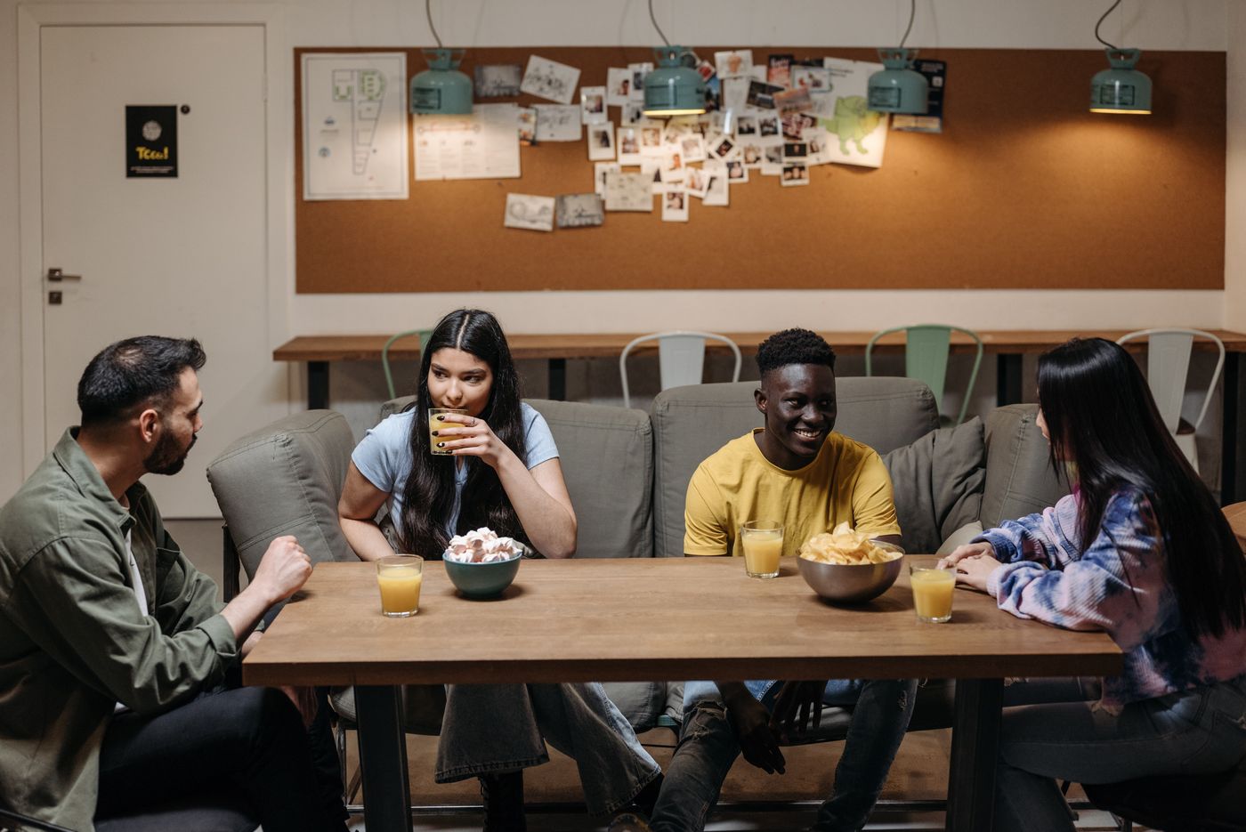 Four adults share drinks and conversation in a comfortable lounge.