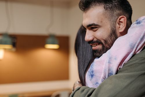 Free Bearded man and partner embracing indoors, displaying affection and happiness. Stock Photo