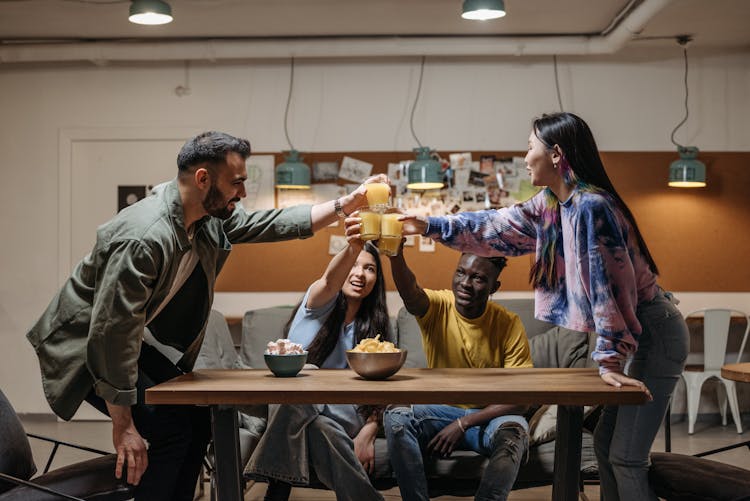 A Group Of Friends Toasting Drinks While Having Conversation