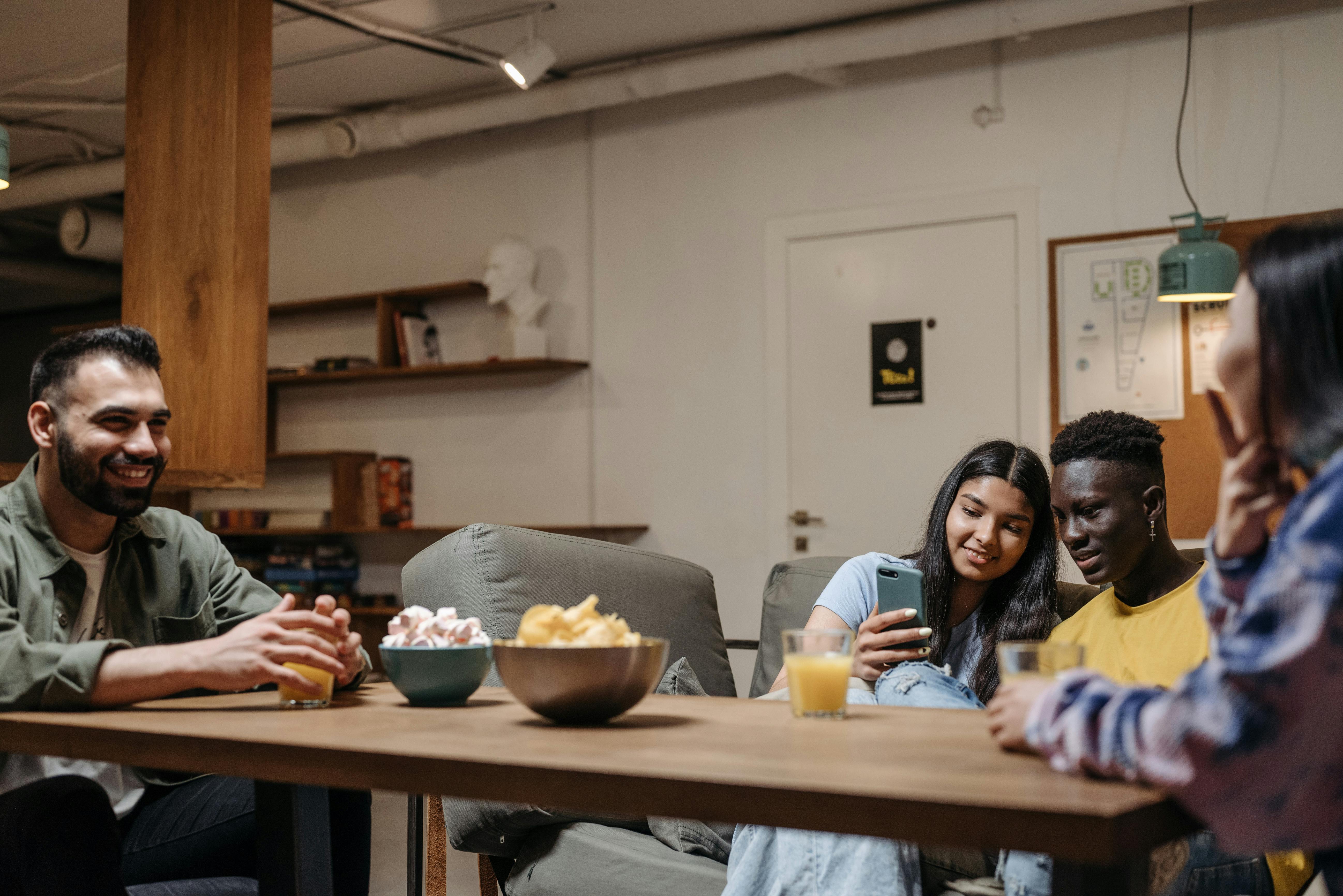 diverse group of friends laughing at a dinner table, warm film grain aesthetic